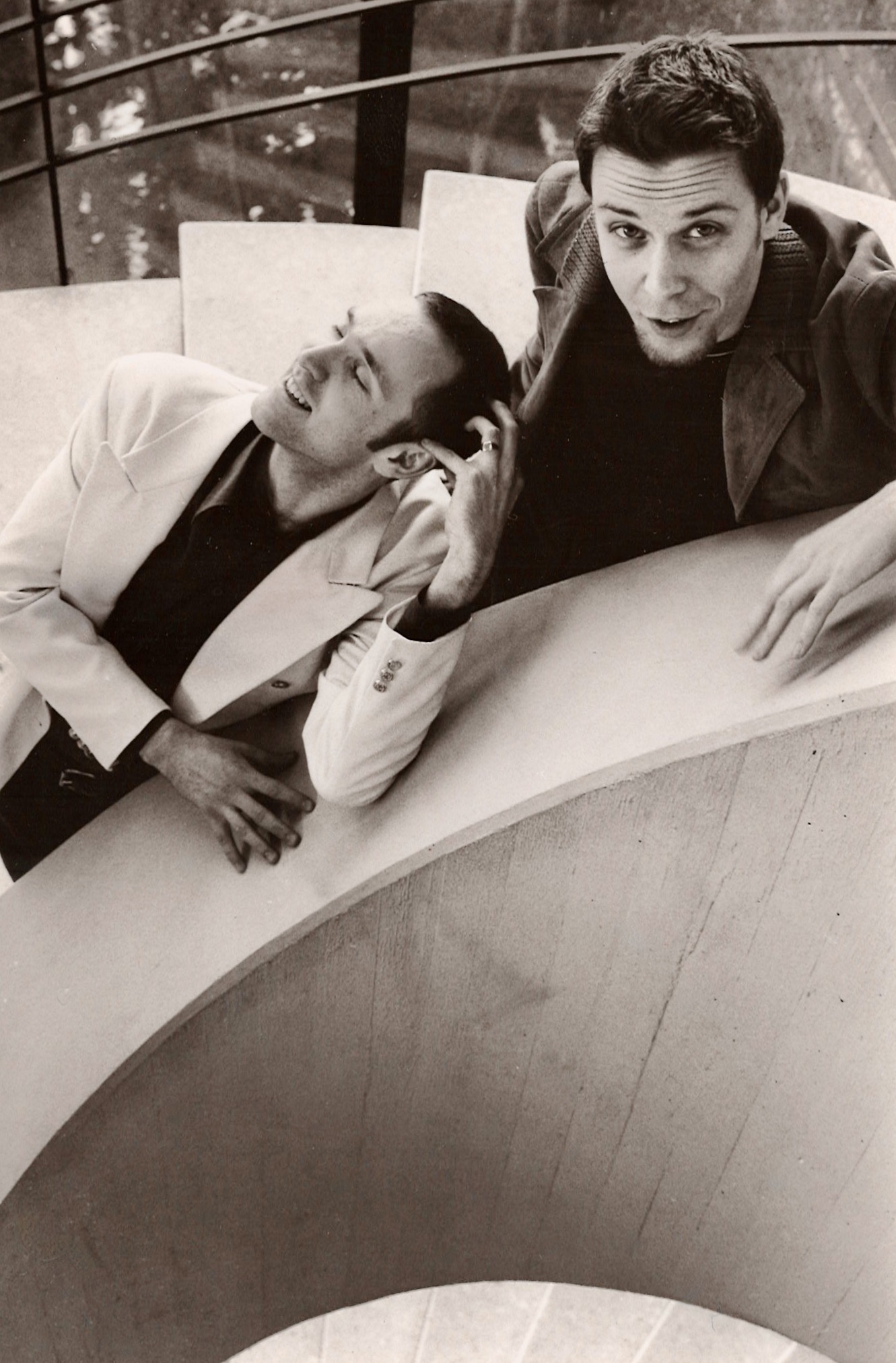 The two musicians by a curved stairwell in a candid black and white photograph